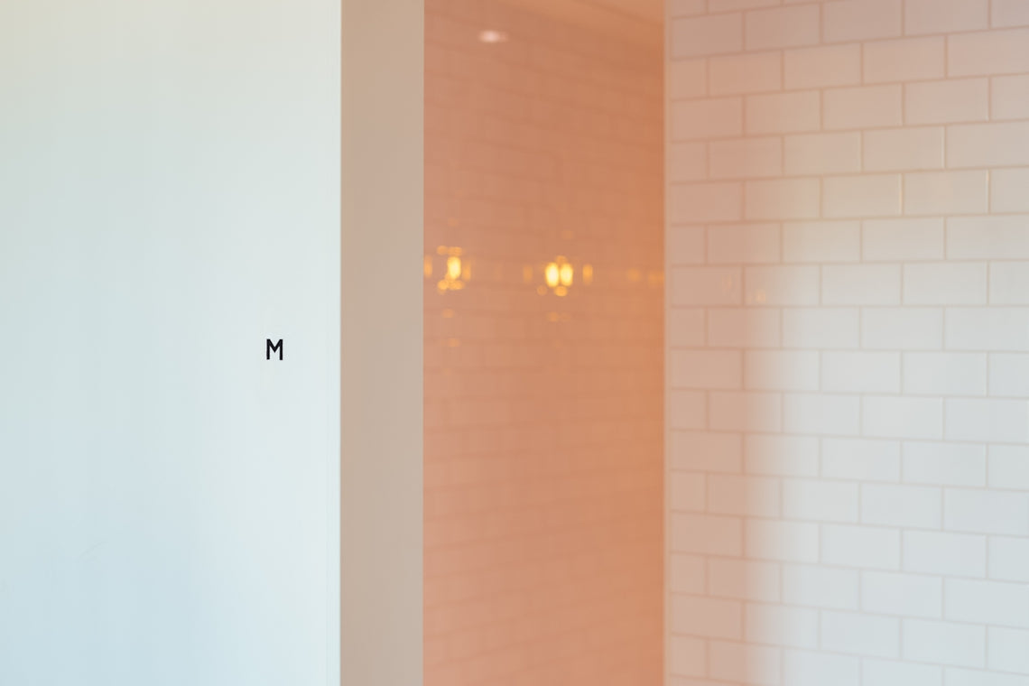 a bathroom with a white wall and a white tiled wall