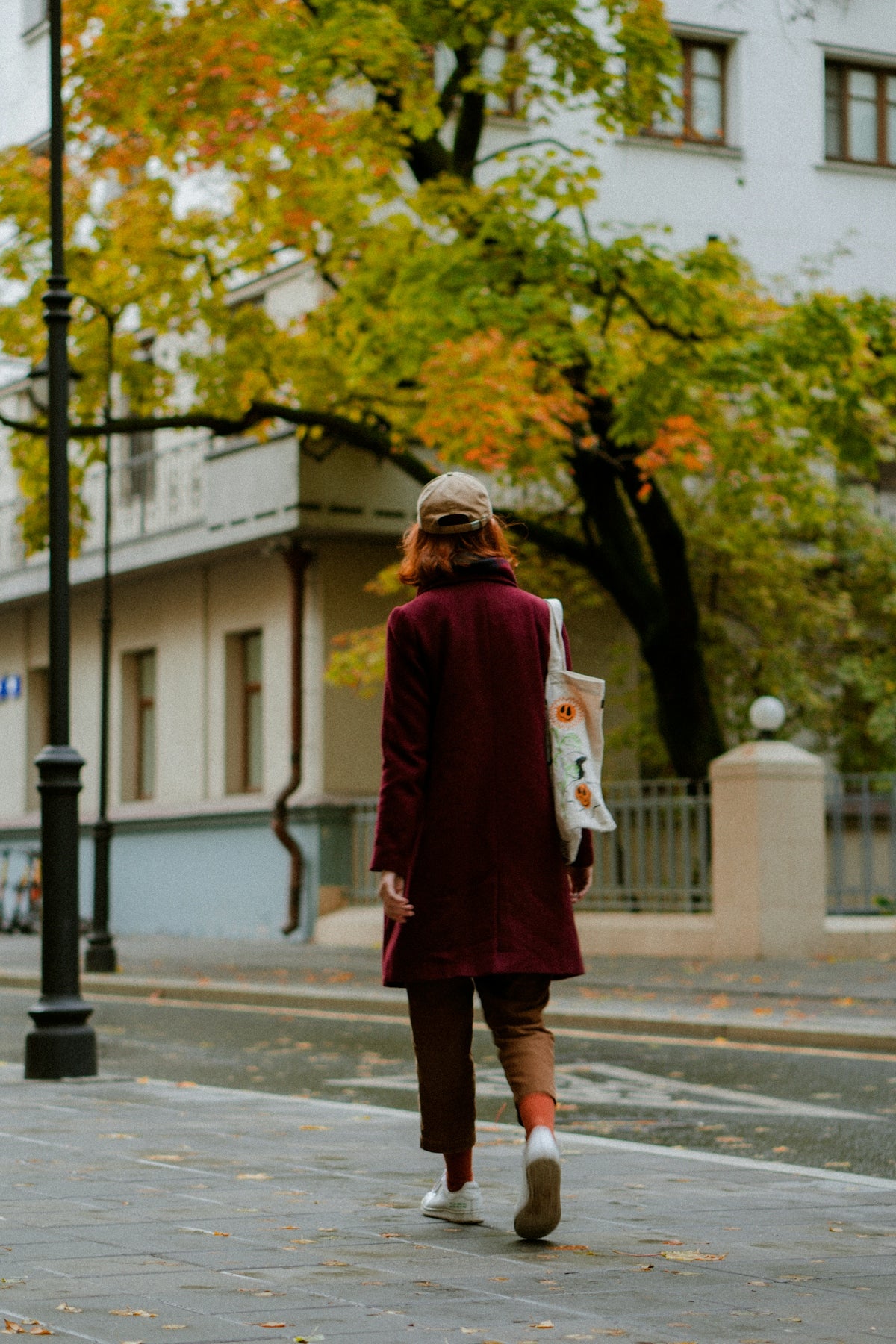 a woman walking down the street in a maroon coat