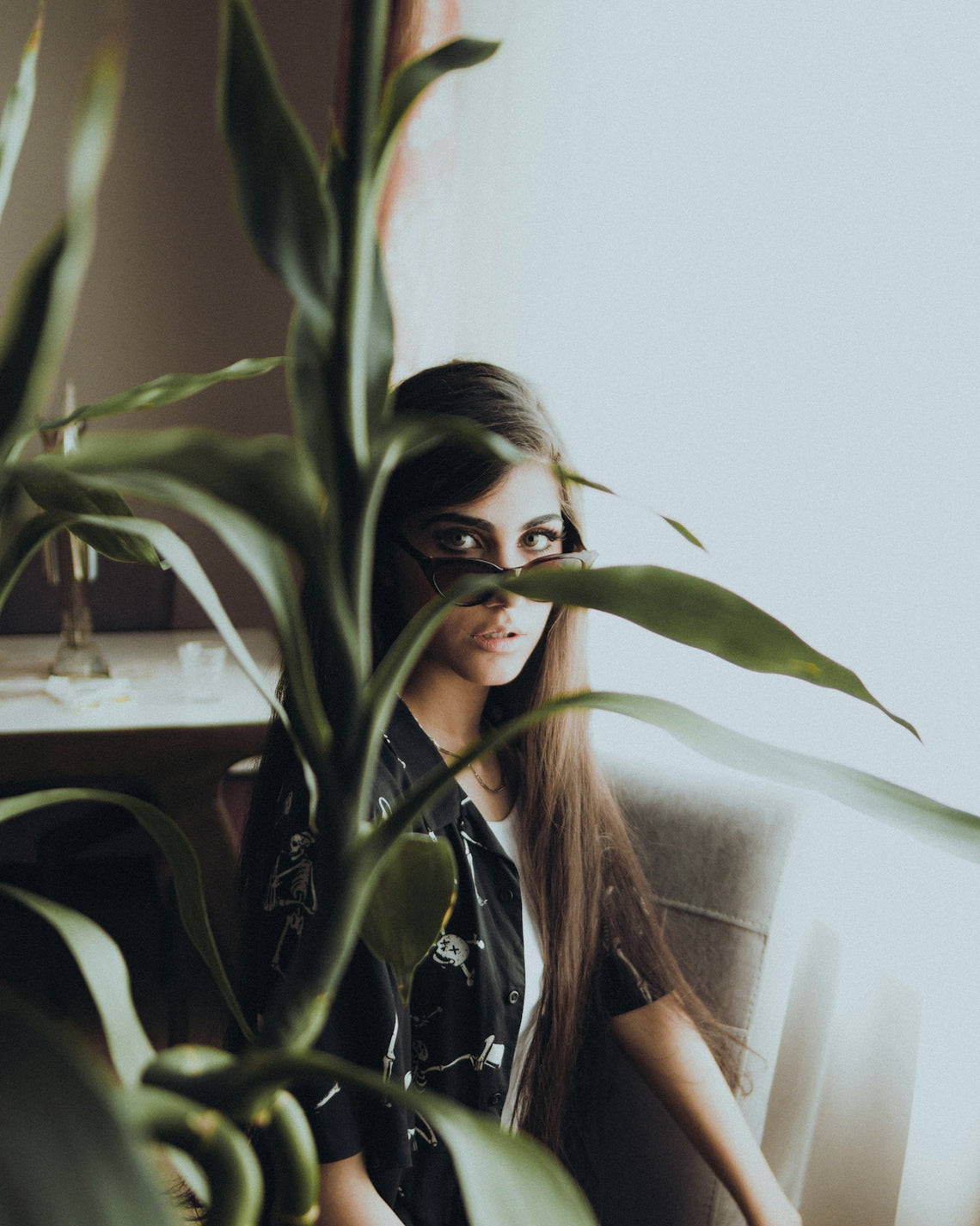 a woman sitting in a chair next to a plant