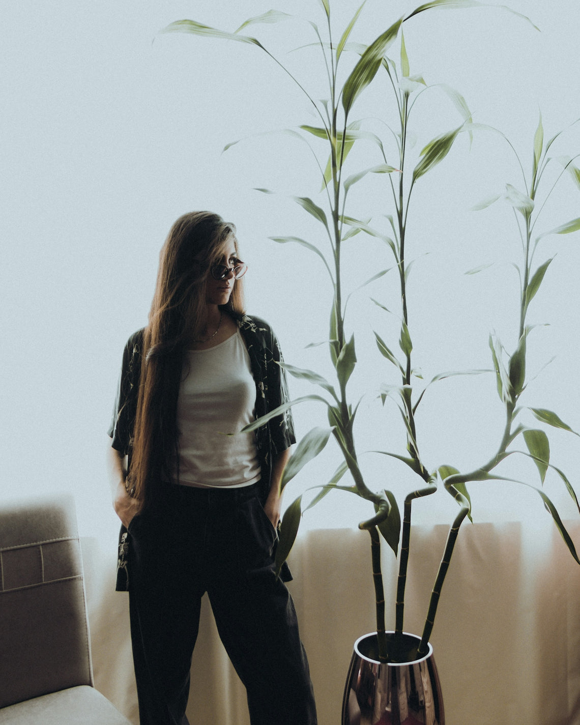 a woman standing next to a plant in a room