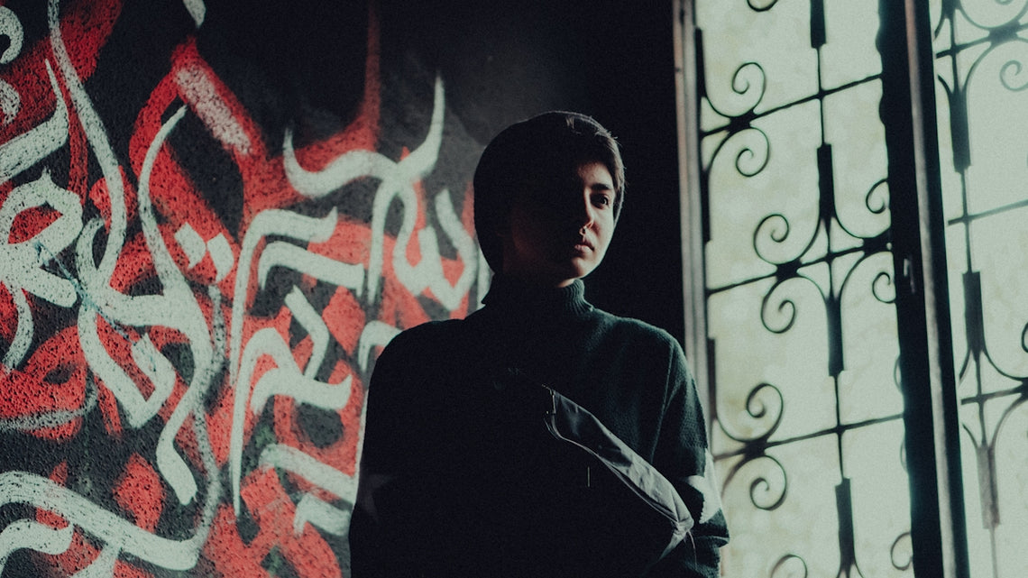 a man standing in front of a wall covered in graffiti
