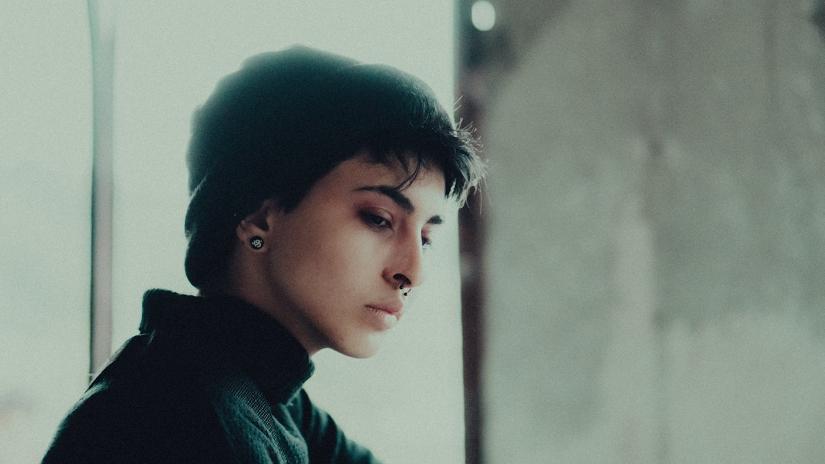 a woman with ear piercings looking out a window