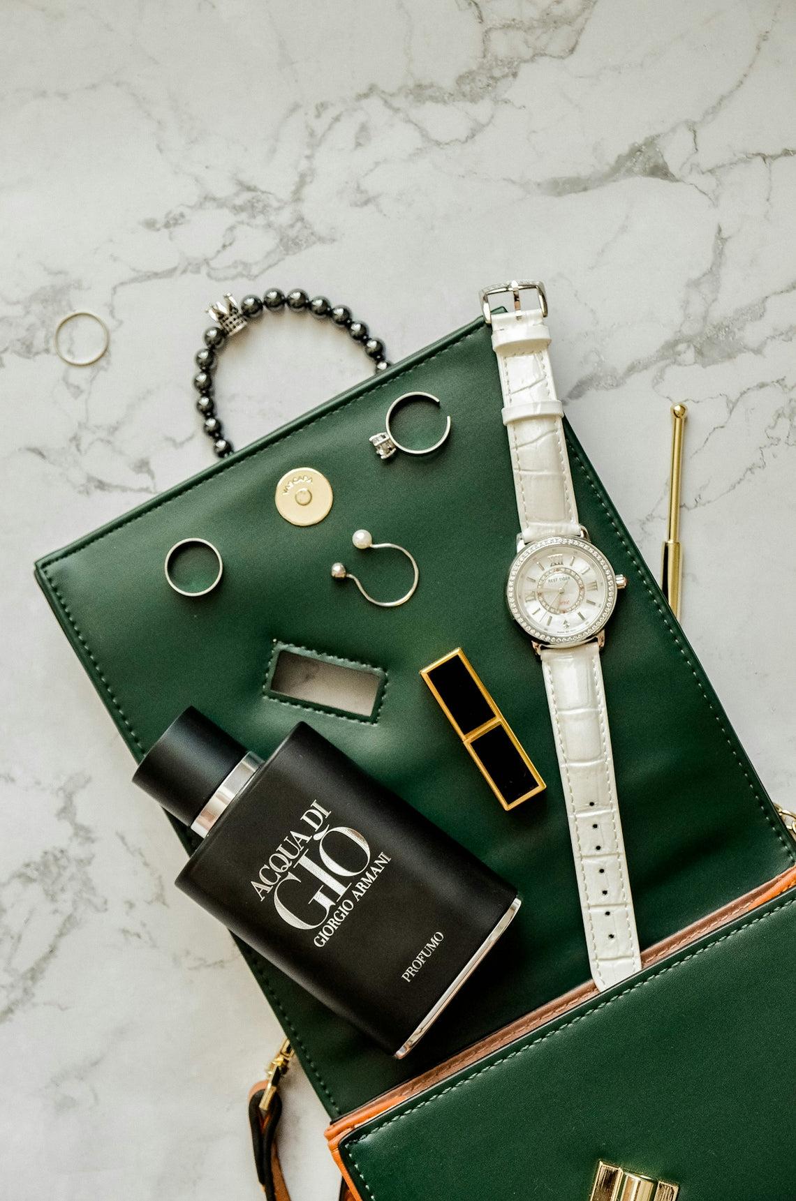 a green purse with a watch and other items