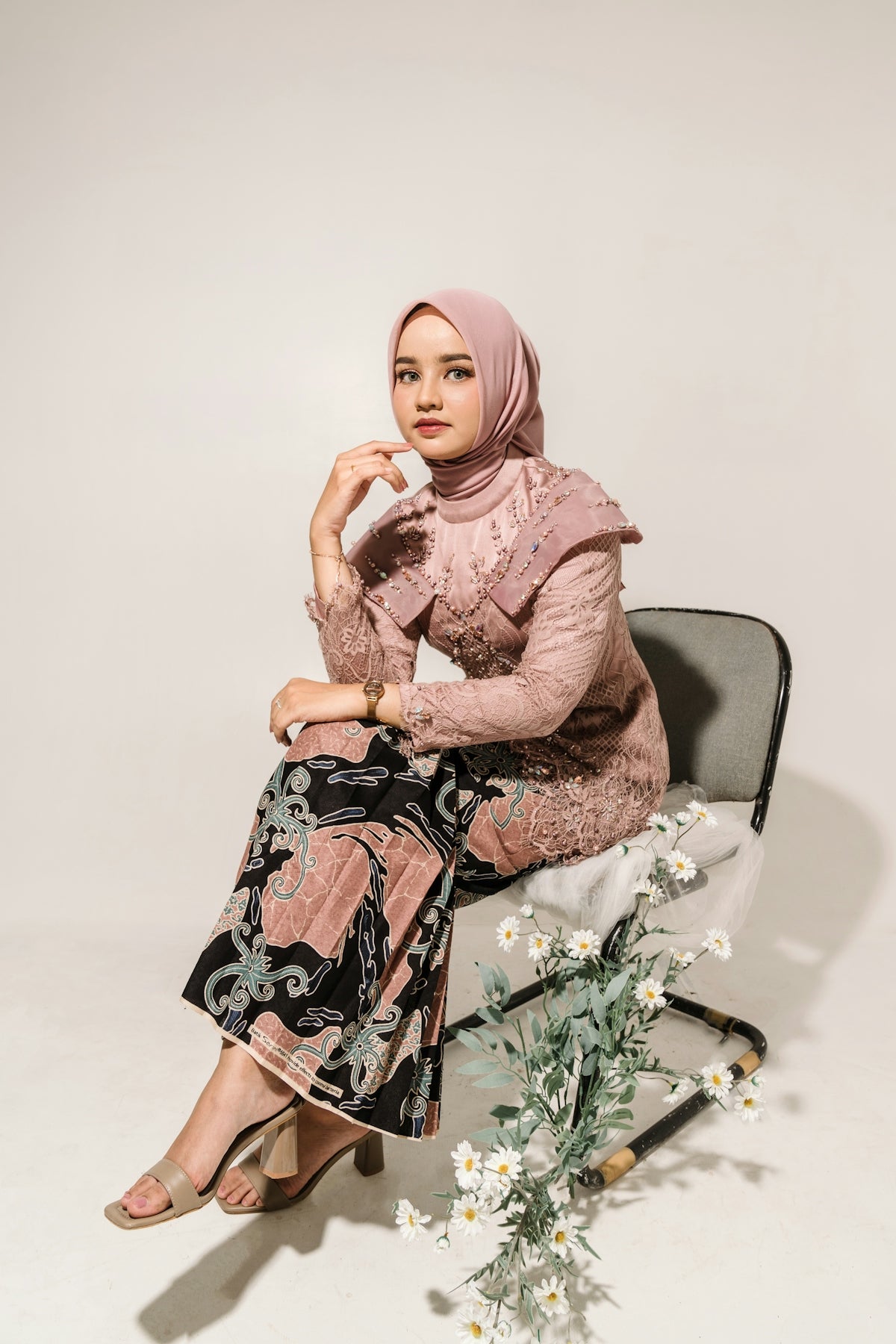 a woman sitting on a chair next to a vase of flowers