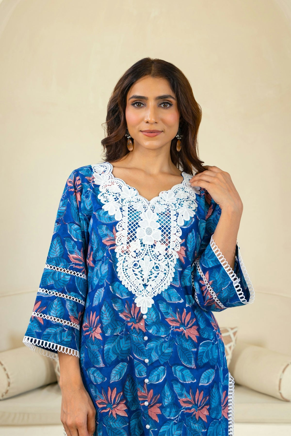 A woman in a blue dress standing in front of a couch