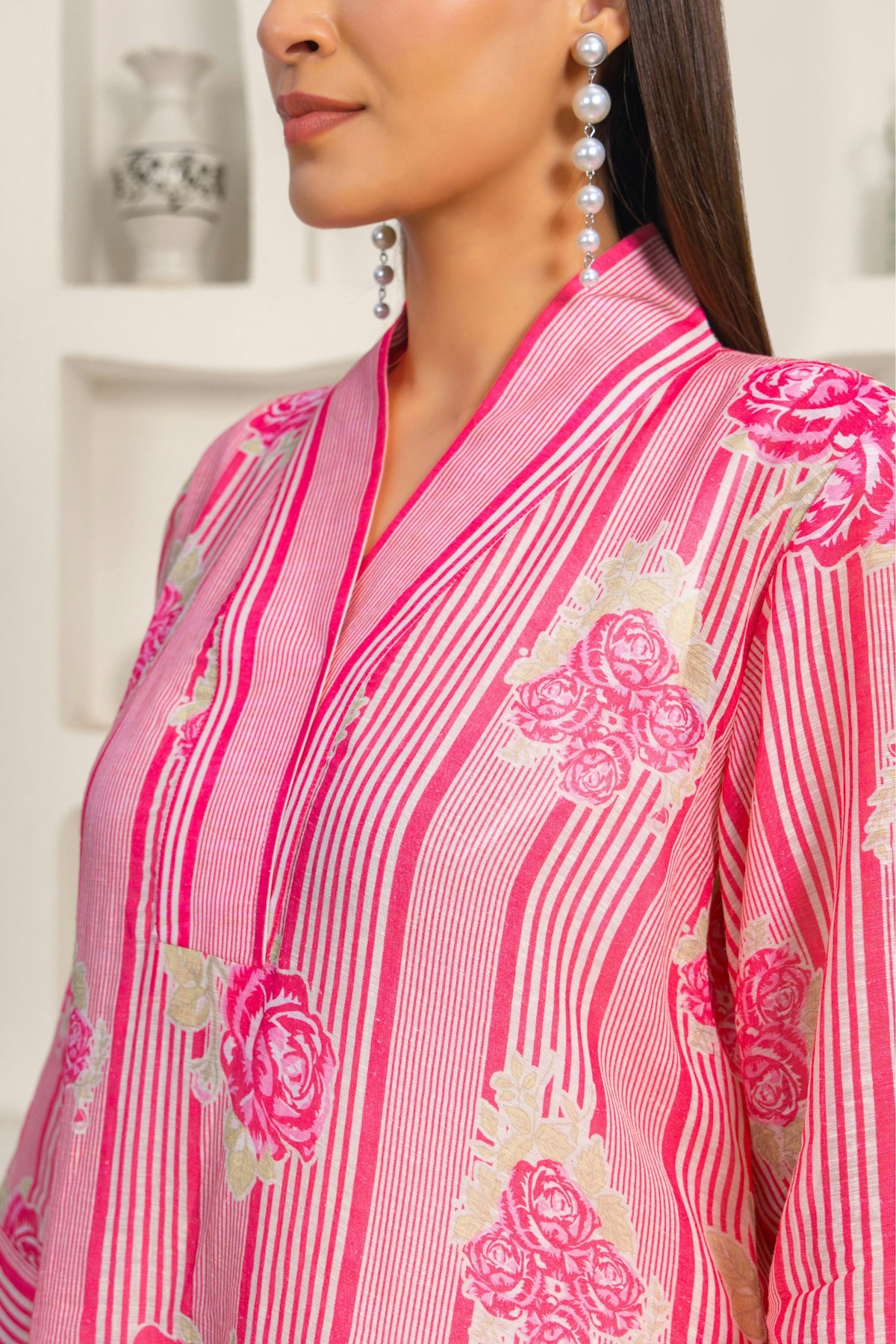 A woman wearing a pink and white shirt and earrings