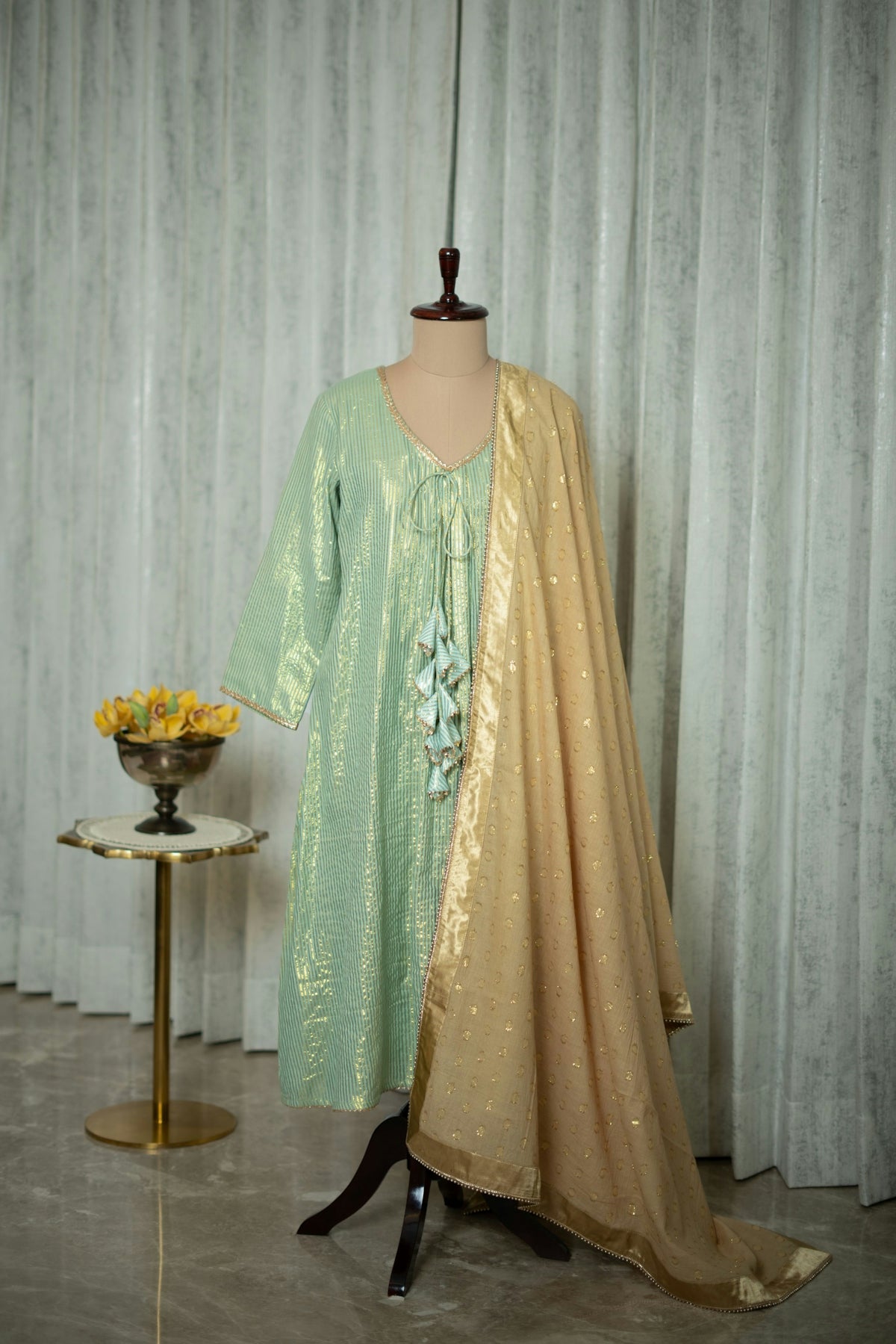 A dress on a mannequin in front of a curtain