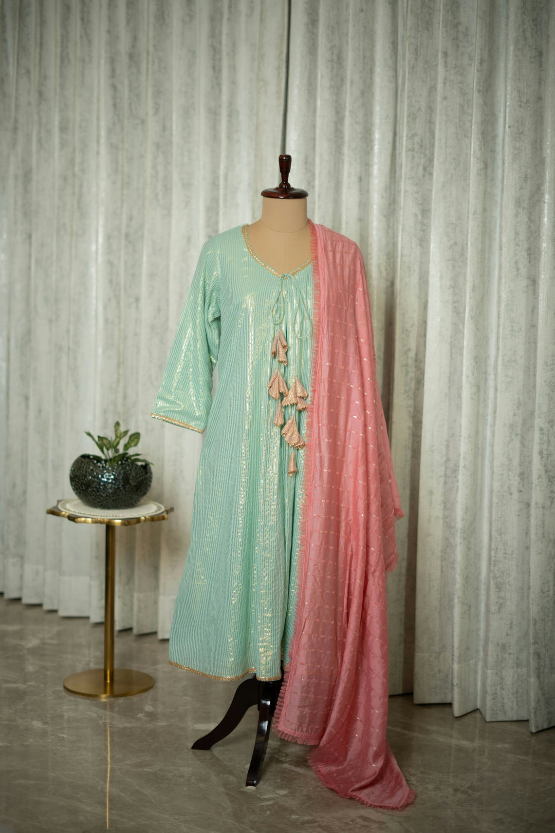 A dress on a mannequin in front of a curtain