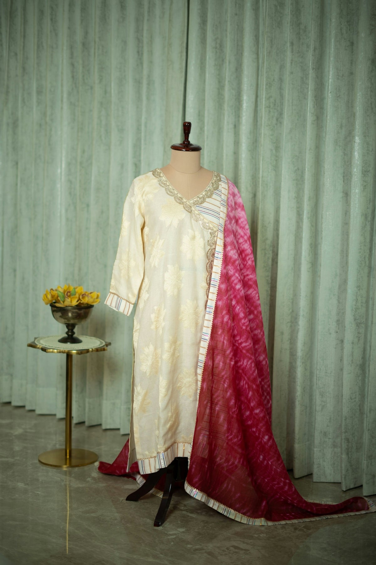 A dress on a mannequin in front of a curtain