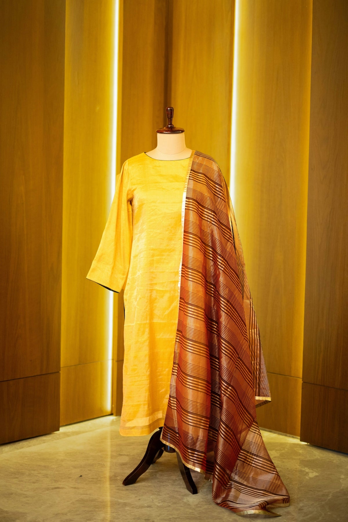 A mannequin wearing a yellow shirt and a plaid scarf
