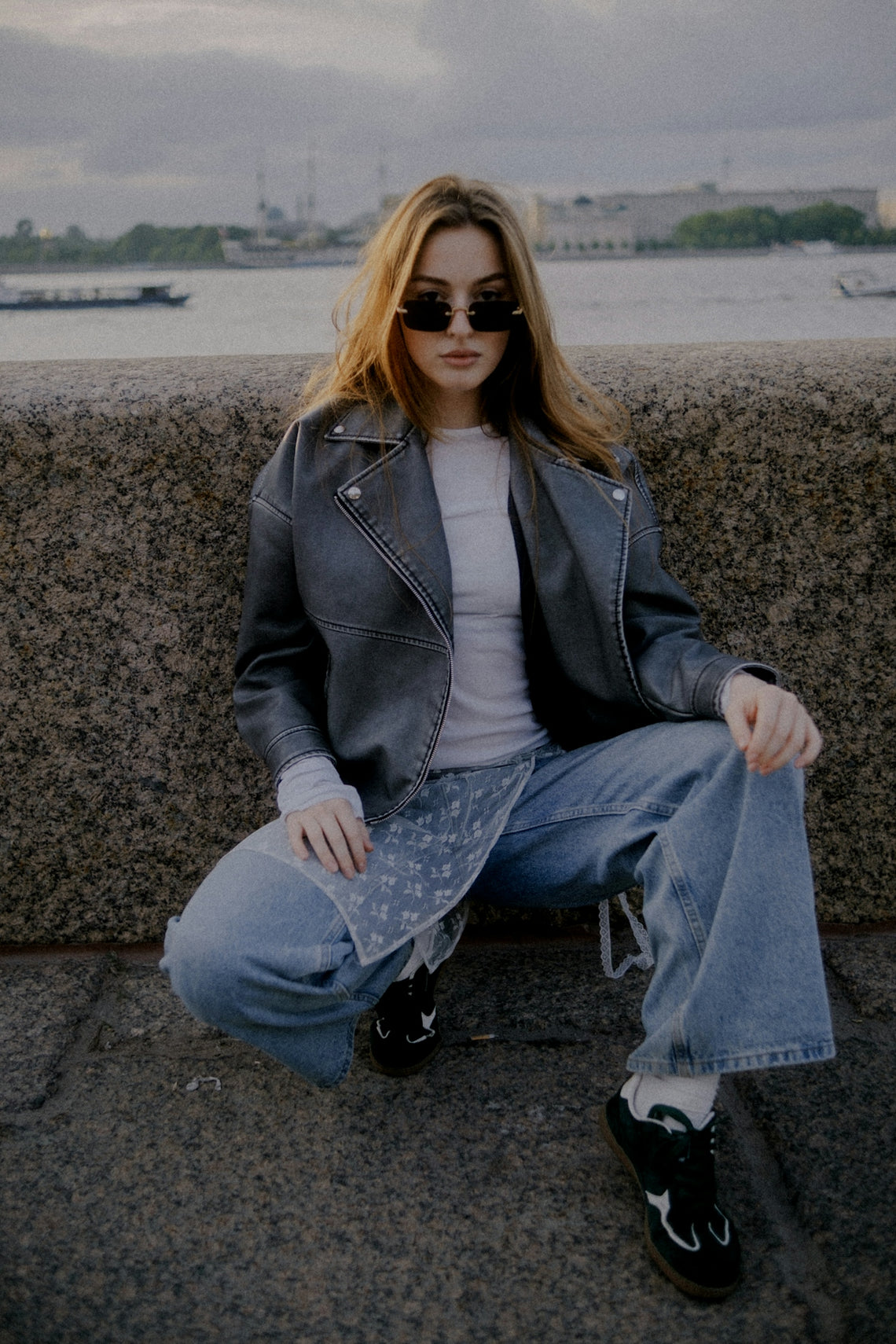 Young woman in sunglasses and leather jacket crouching