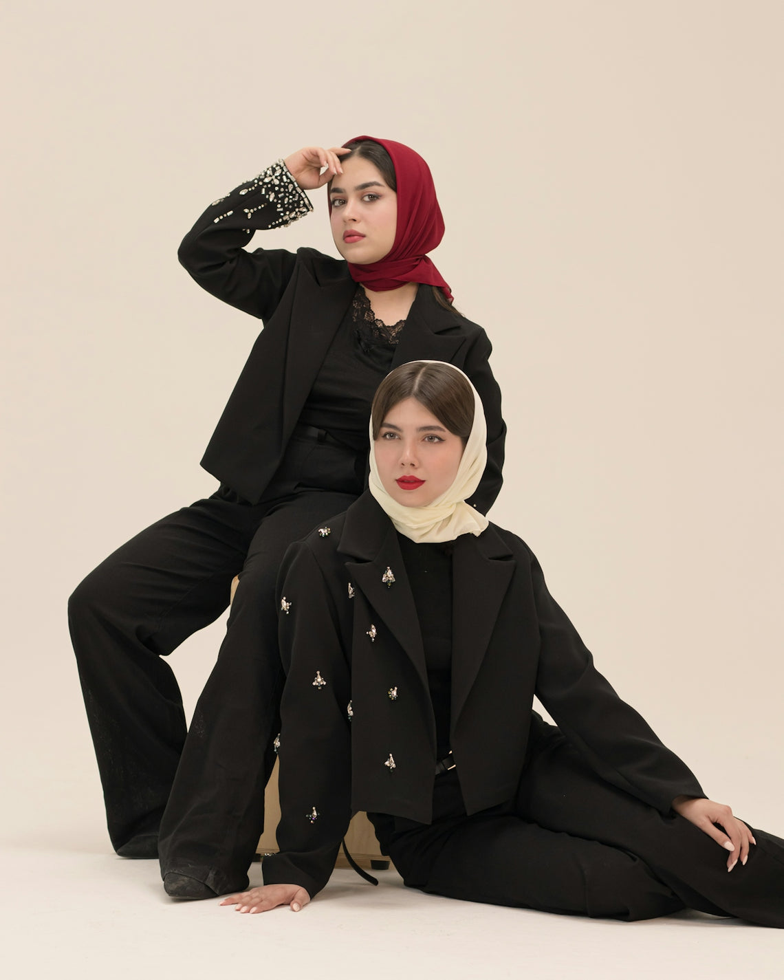 Two women in black suits and headscarves posing.