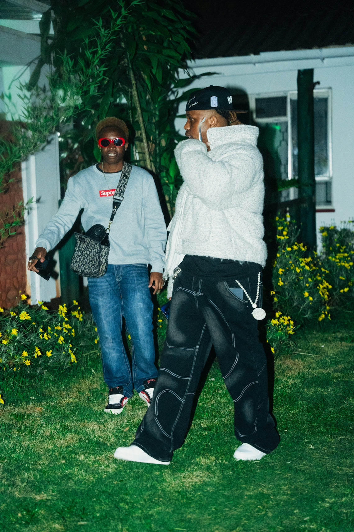 Two men in casual streetwear standing in a garden.