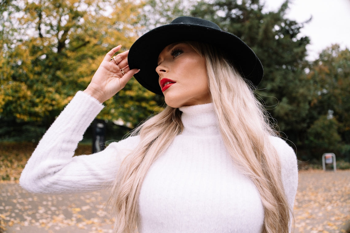 Woman in white turtleneck and black hat outdoors