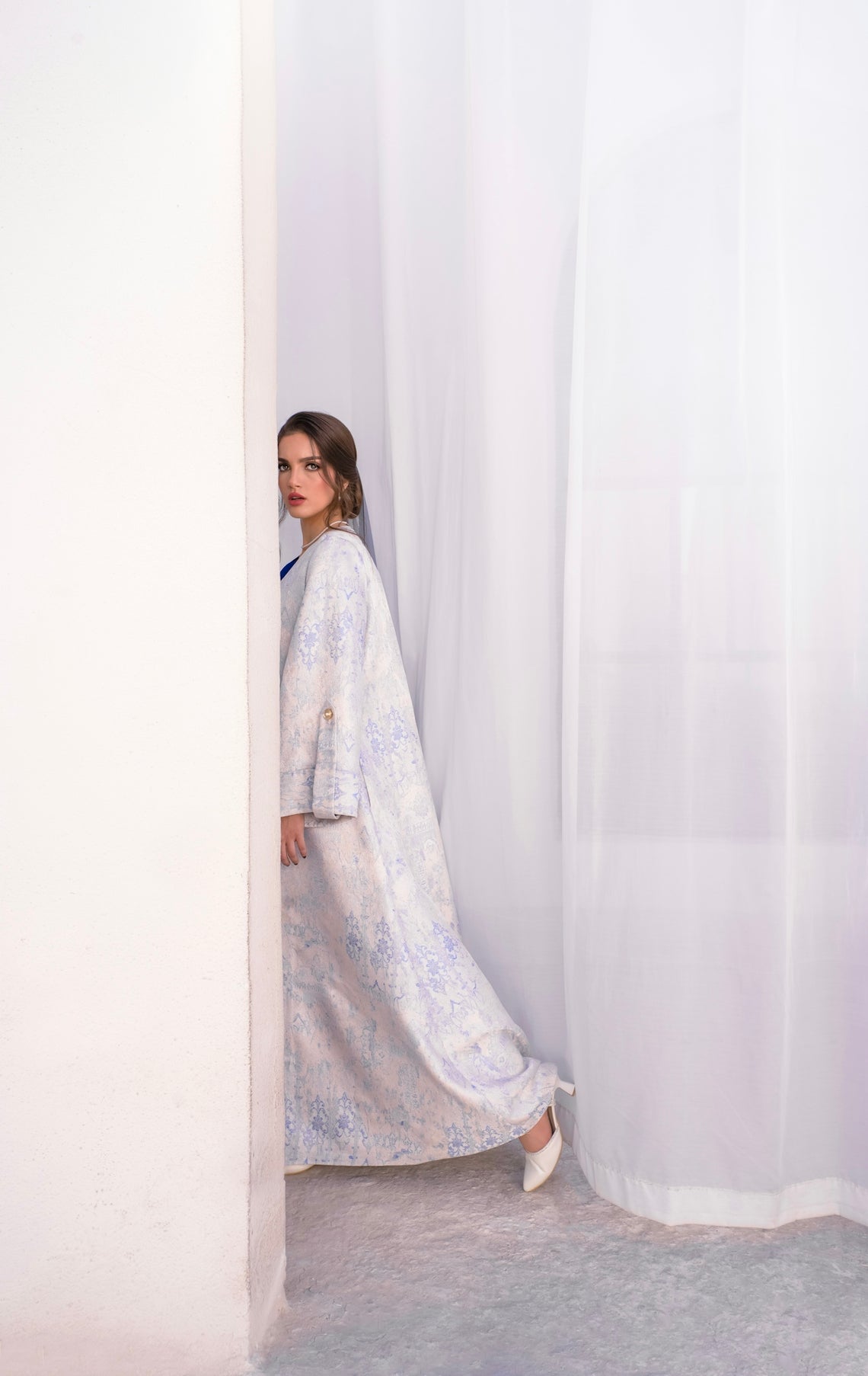 Woman in a patterned dress peeking around a corner