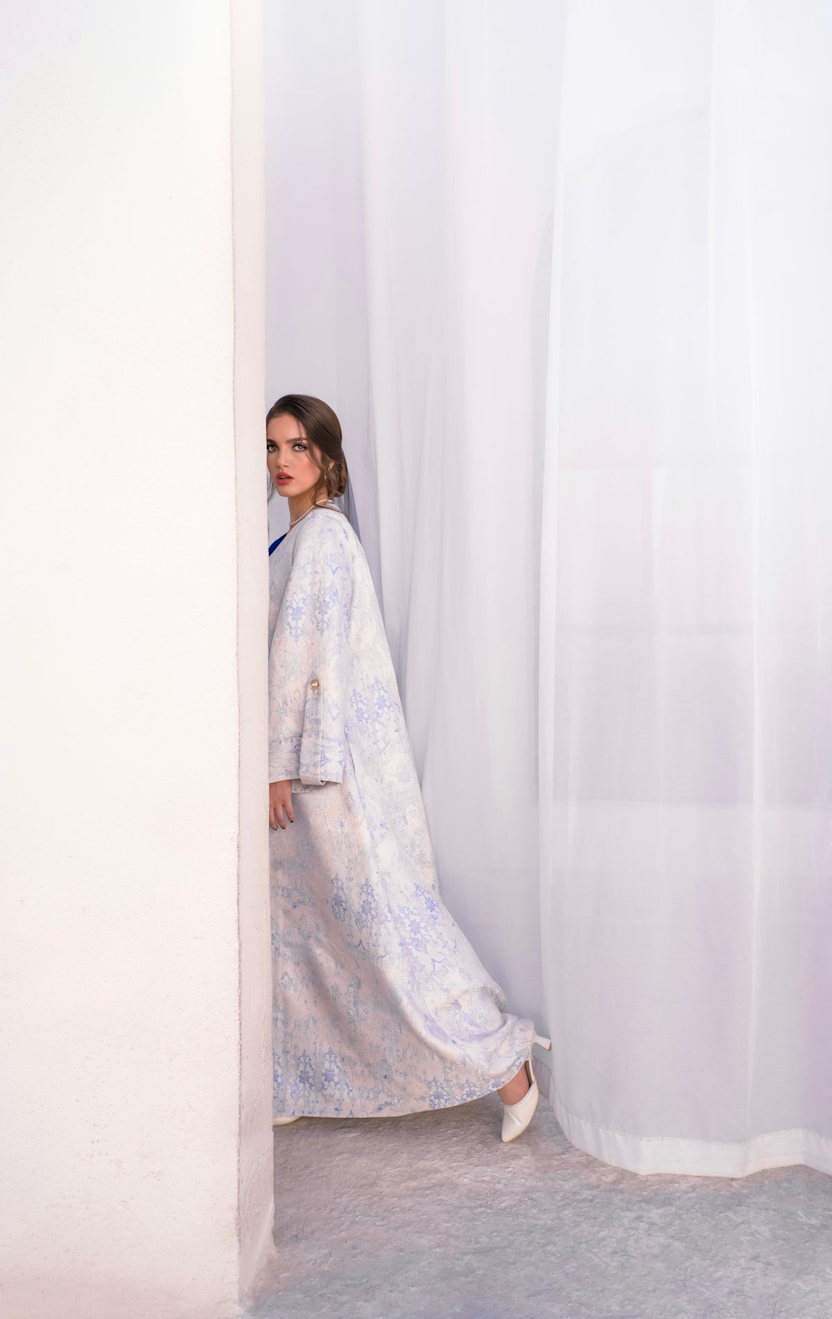 Woman in a patterned dress peeking around a corner