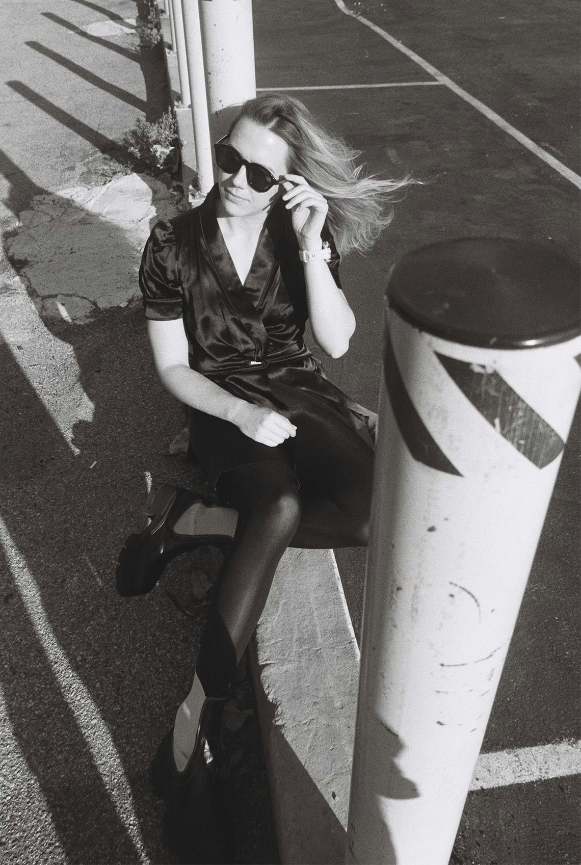 Woman in sunglasses and black dress sitting outdoors