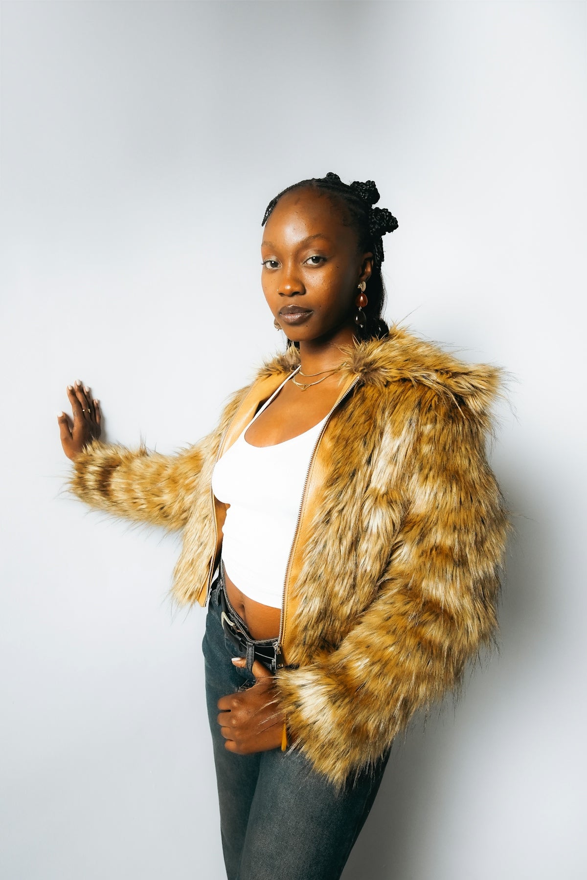 Young woman in a furry jacket and jeans poses.