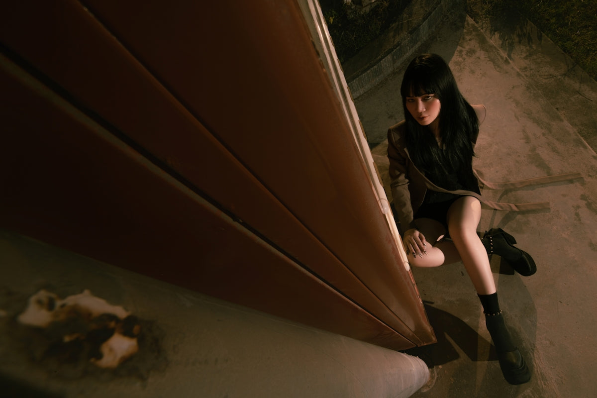 A young woman crouches on a ledge at night.