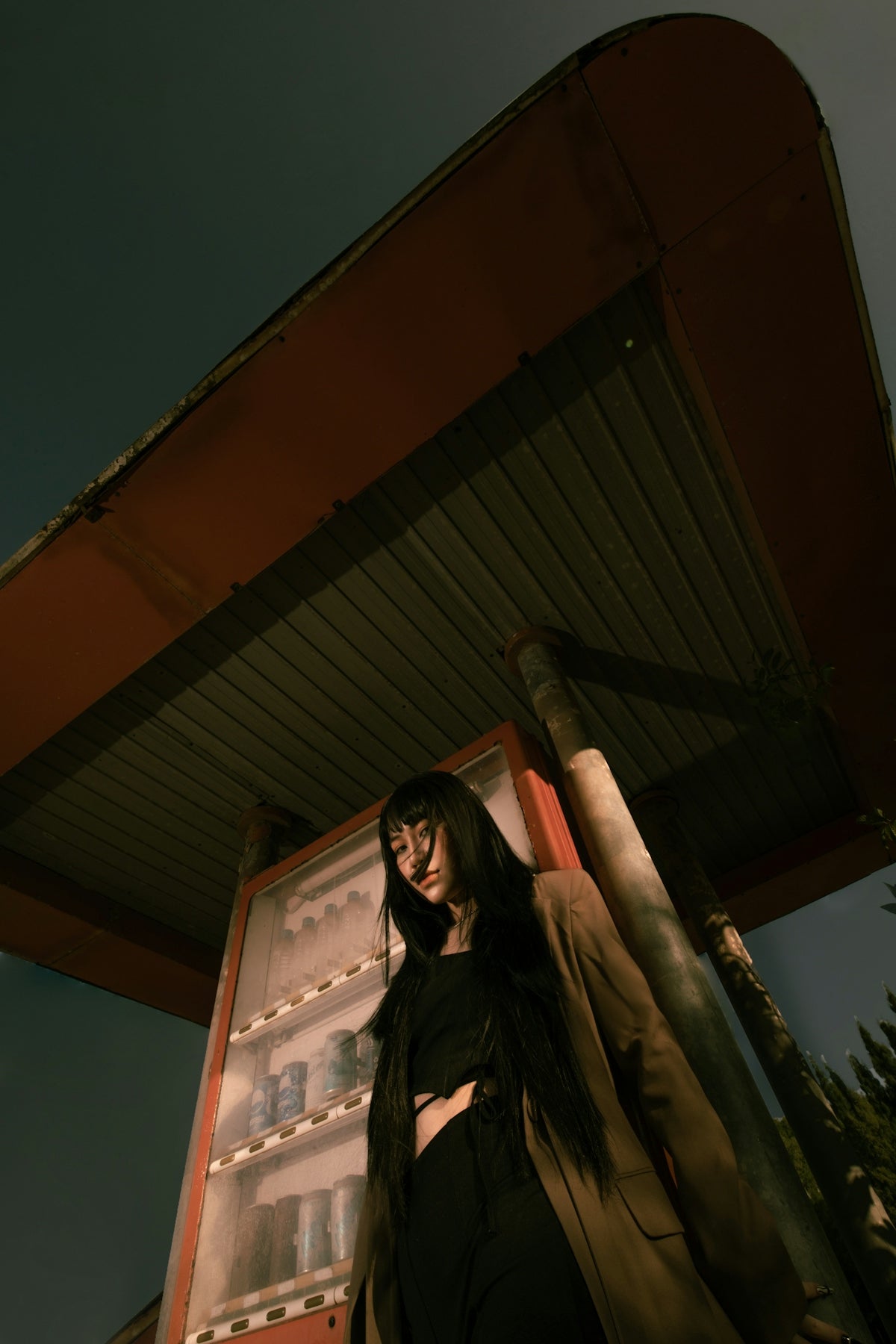Woman standing by a vending machine at night